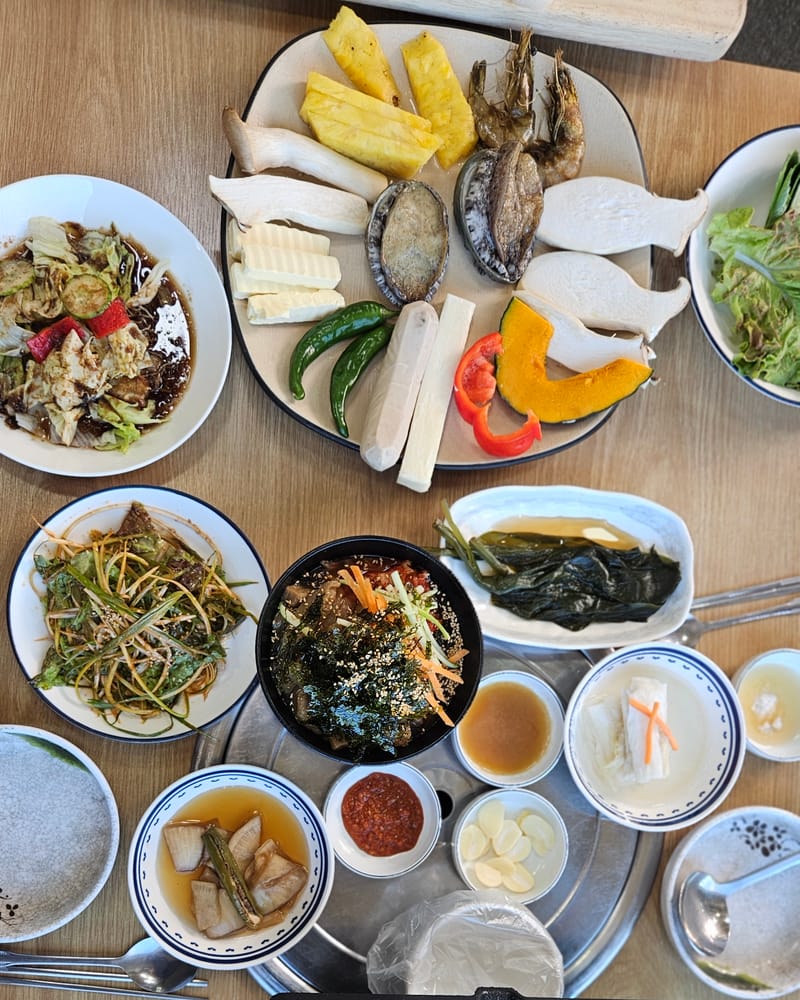 반찬과 활전복 곁들임이 차려진 옥길장터식당 테이블
